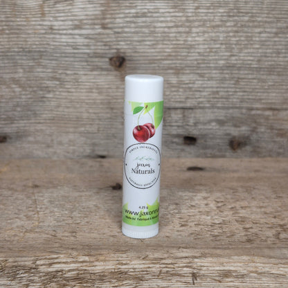 Jaxon Naturals Cherry Lip Balm in a recyclable tube, handcrafted with natural ingredients and displayed on rustic barn wood.