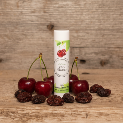 Jaxon Naturals Cherry Lip Balm in a recyclable tube, handcrafted with natural ingredients and displayed on rustic barn wood with fresh and dried cherries.