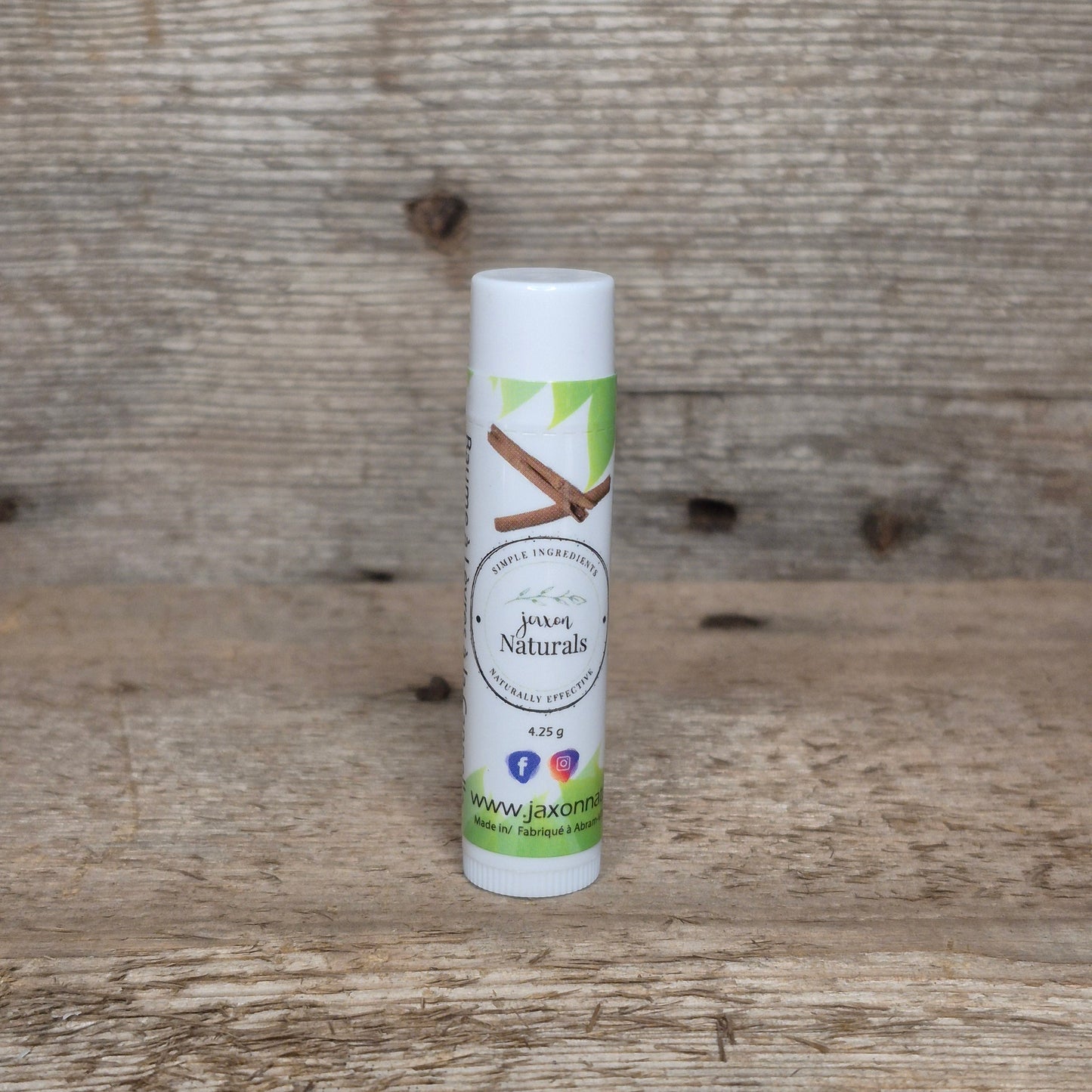 Jaxon Naturals Cinnamon Lip Balm in a recyclable tube, handcrafted with natural ingredients and displayed on rustic barn wood.