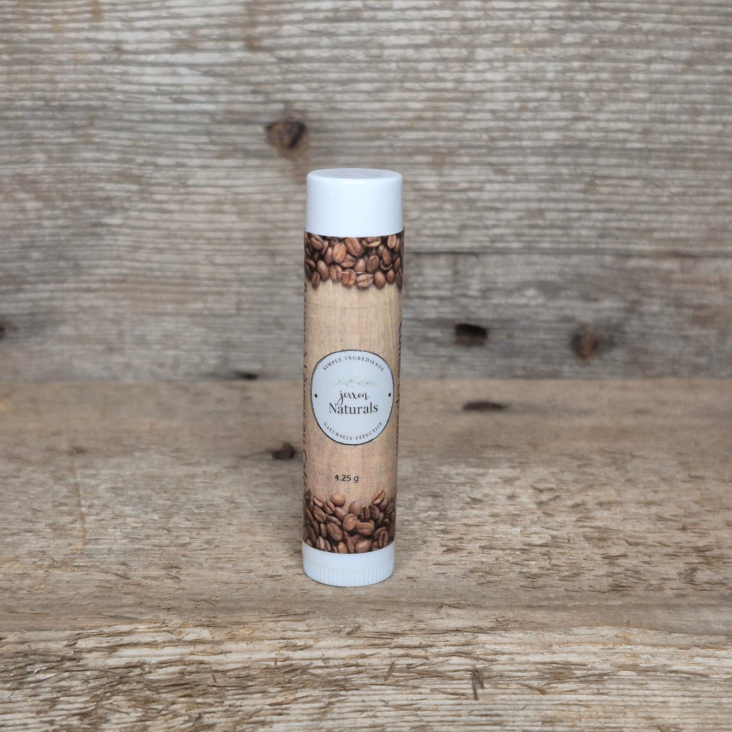 Jaxon Naturals Coffee Lip Balm in a recyclable tube, handcrafted with natural ingredients and displayed on rustic barn wood.