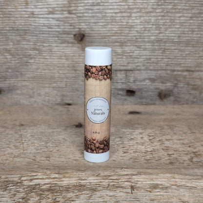 Jaxon Naturals Coffee Lip Balm in a recyclable tube, handcrafted with natural ingredients and displayed on rustic barn wood.