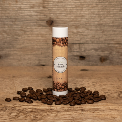 Jaxon Naturals Coffee Lip Balm in a recyclable tube, handcrafted with natural ingredients and displayed on rustic barn wood with roasted coffee beans.