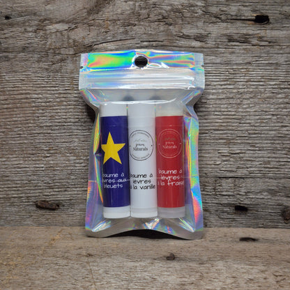 Jaxon Naturals Acadian lip balm collection with three handcrafted Acadian-inspired lip balms displayed on rustic barn board.