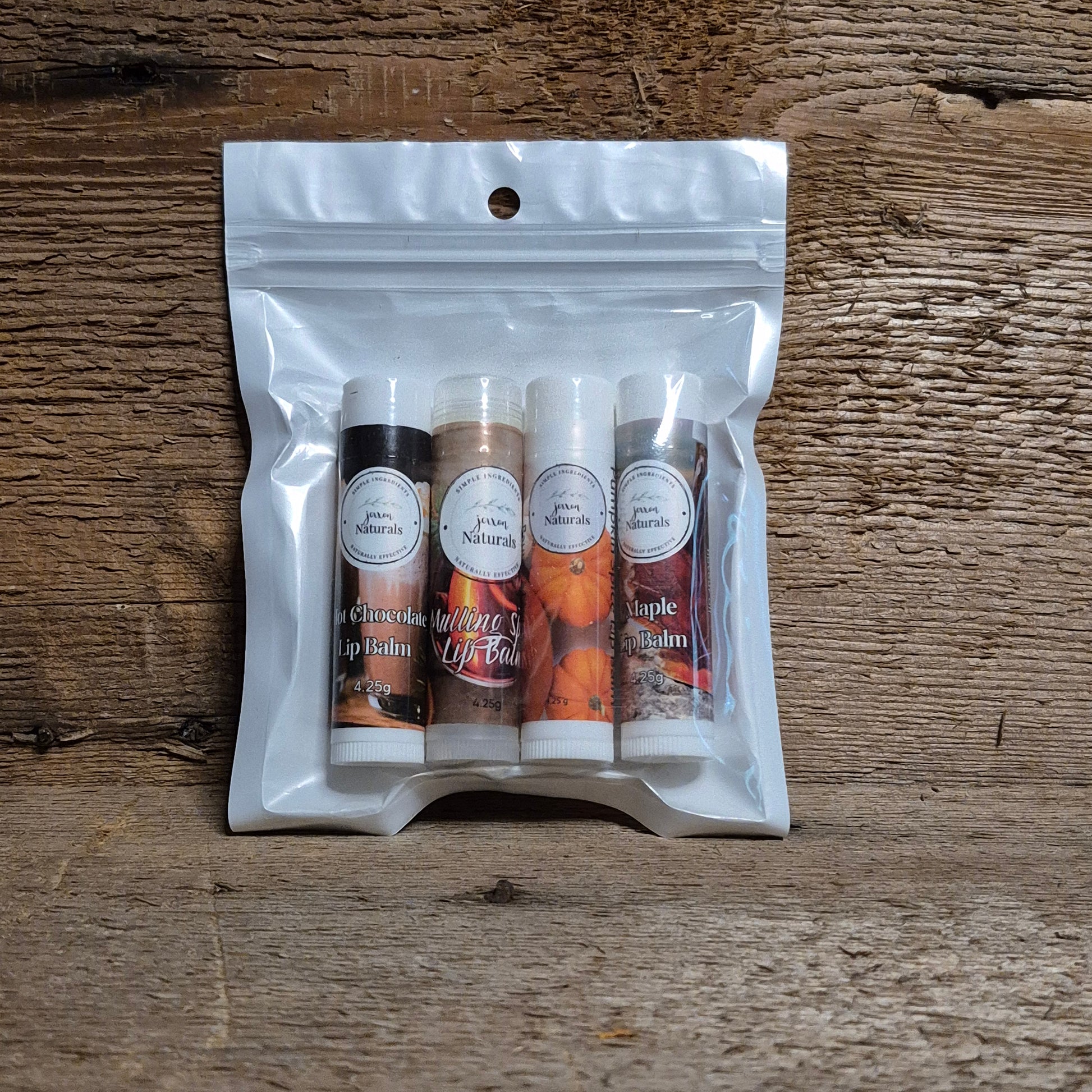 Jaxon Naturals Fall Lip Balm Collection featuring four handcrafted seasonal lip balms displayed on rustic barn board.