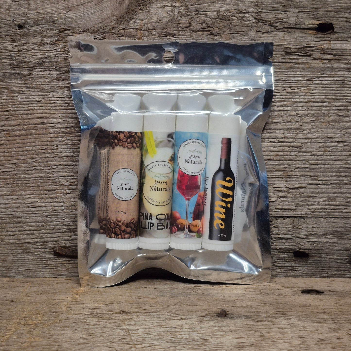 Jaxon Naturals Adult Lip Balm Collection featuring four handcrafted lip balms displayed on rustic barn board.