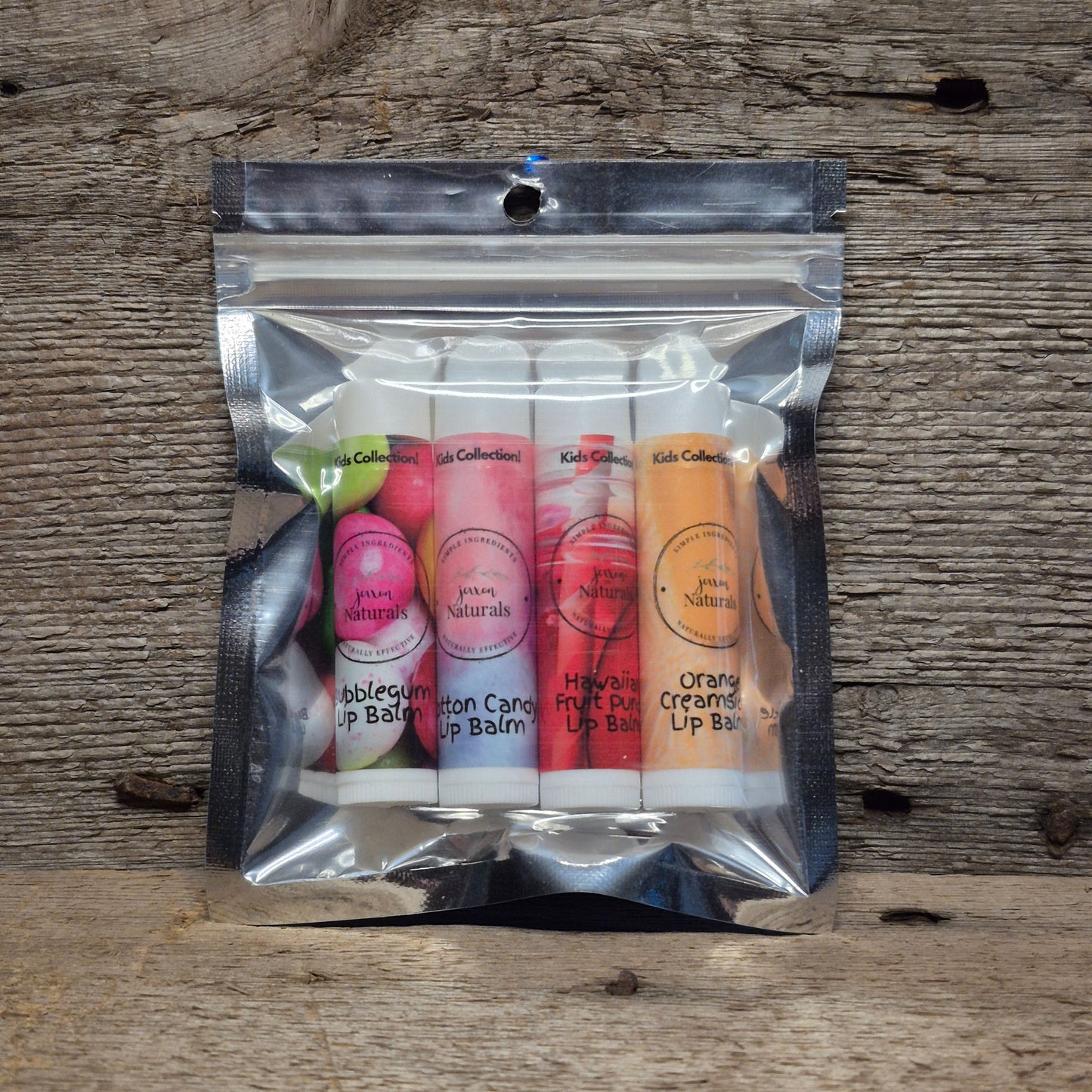 Jaxon Naturals Kids Lip Balm Collection featuring four handcrafted lip balms displayed on rustic barn board.