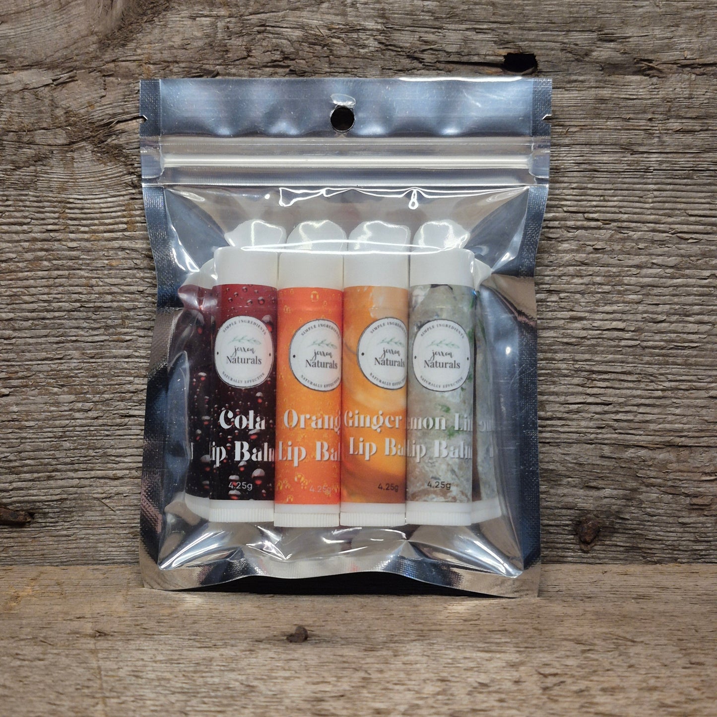 Jaxon Naturals Pop Lip Balm Collection featuring four handcrafted lip balms displayed on rustic barn board.