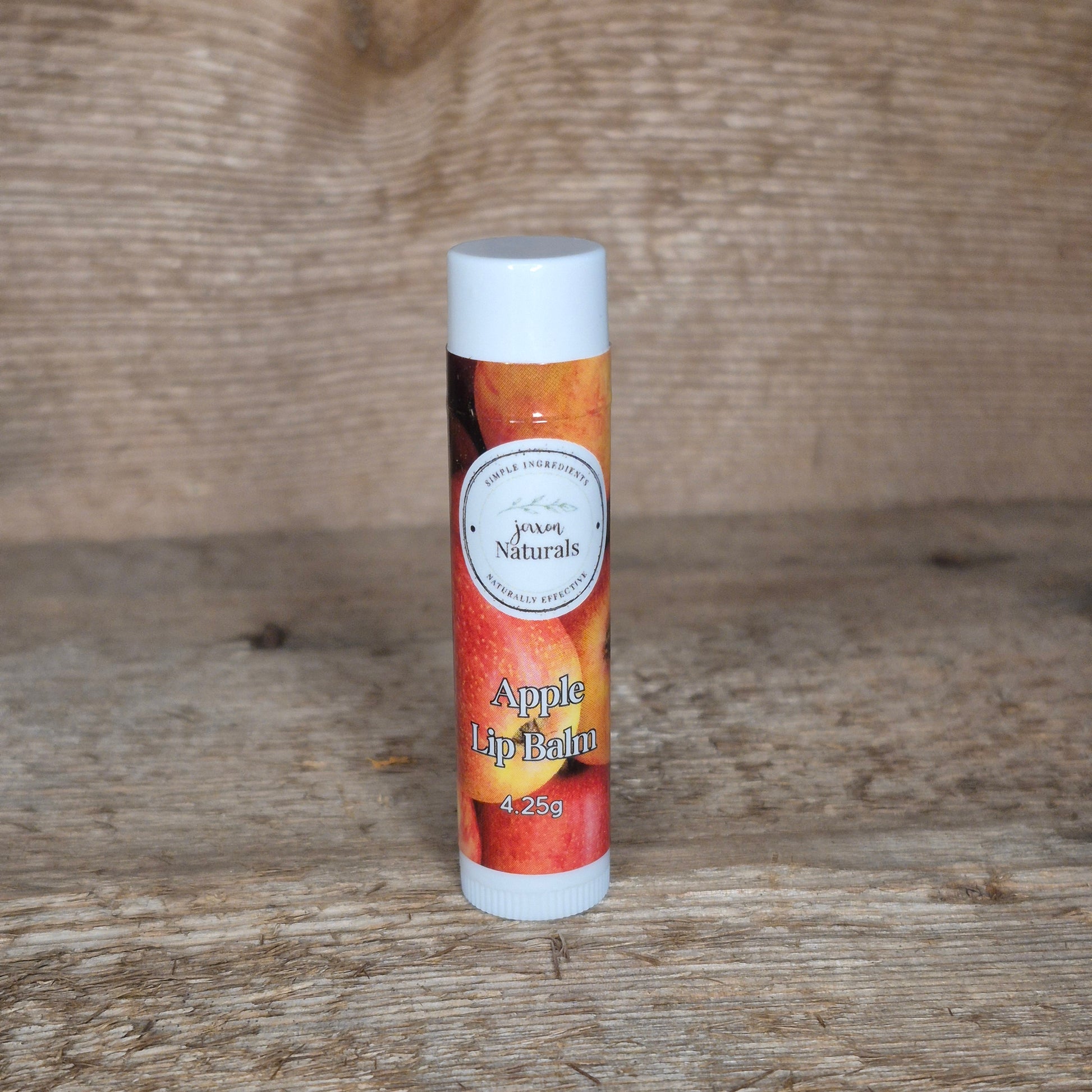 Jaxon Naturals limited edition apple lip balm displayed on rustic barn board.