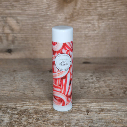 Jaxon Naturals limited edition candy cane lip balm displayed on rustic barn board.