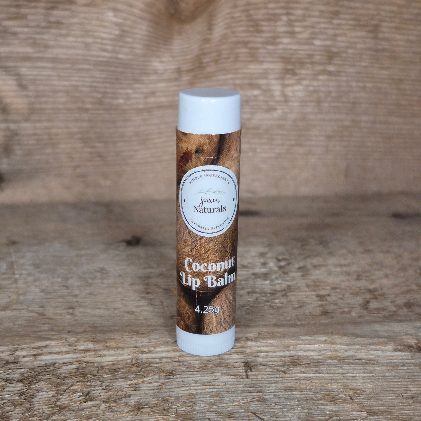 Jaxon Naturals limited edition coconut lip balm displayed on rustic barn board.