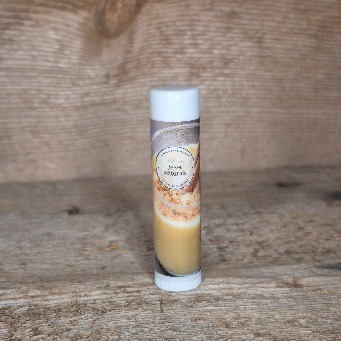 Jaxon Naturals limited edition eggnog lip balm displayed on rustic barn board.