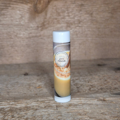 Jaxon Naturals limited edition eggnog lip balm displayed on rustic barn board.