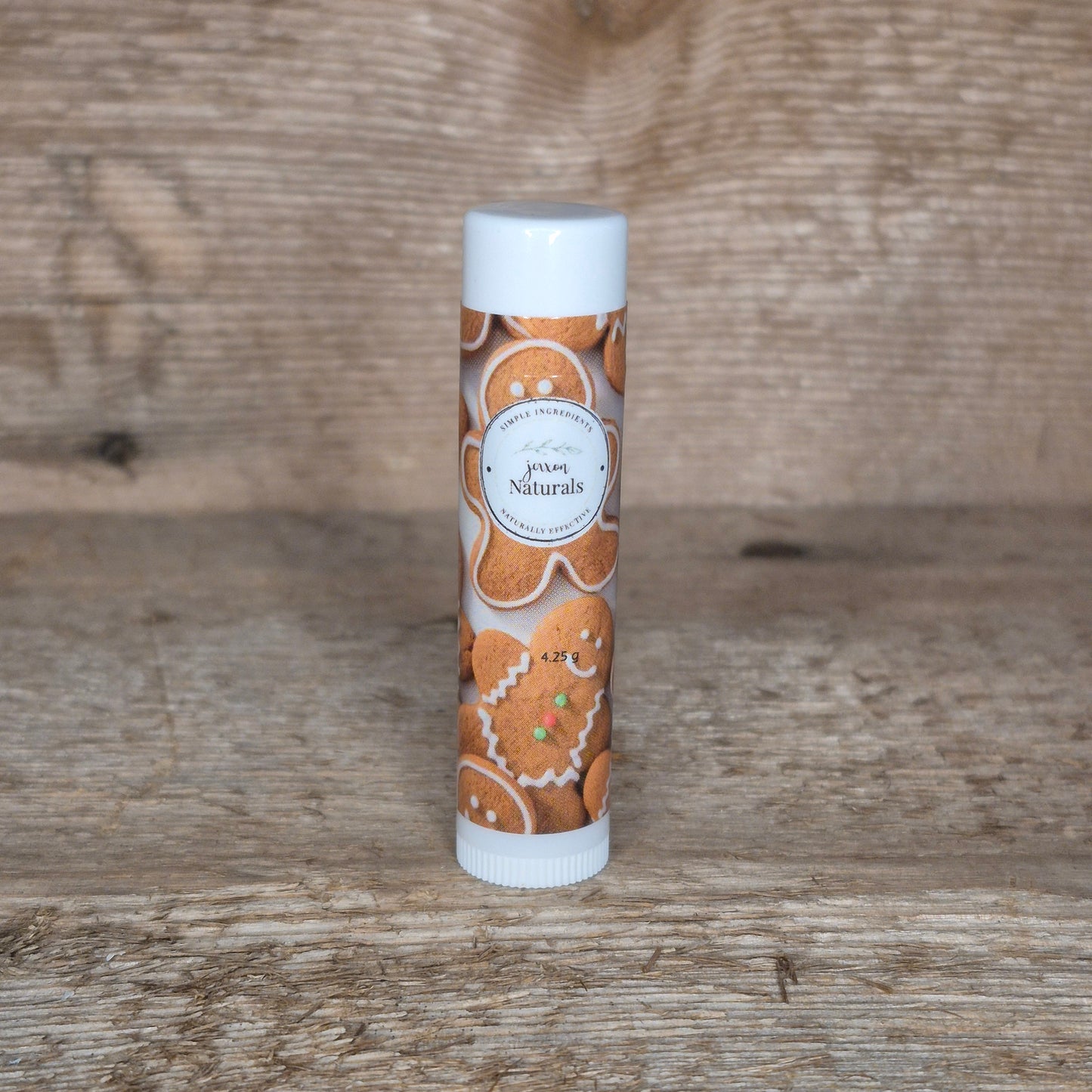 Jaxon Naturals limited edition gingerbread lip balm displayed on rustic barn board.