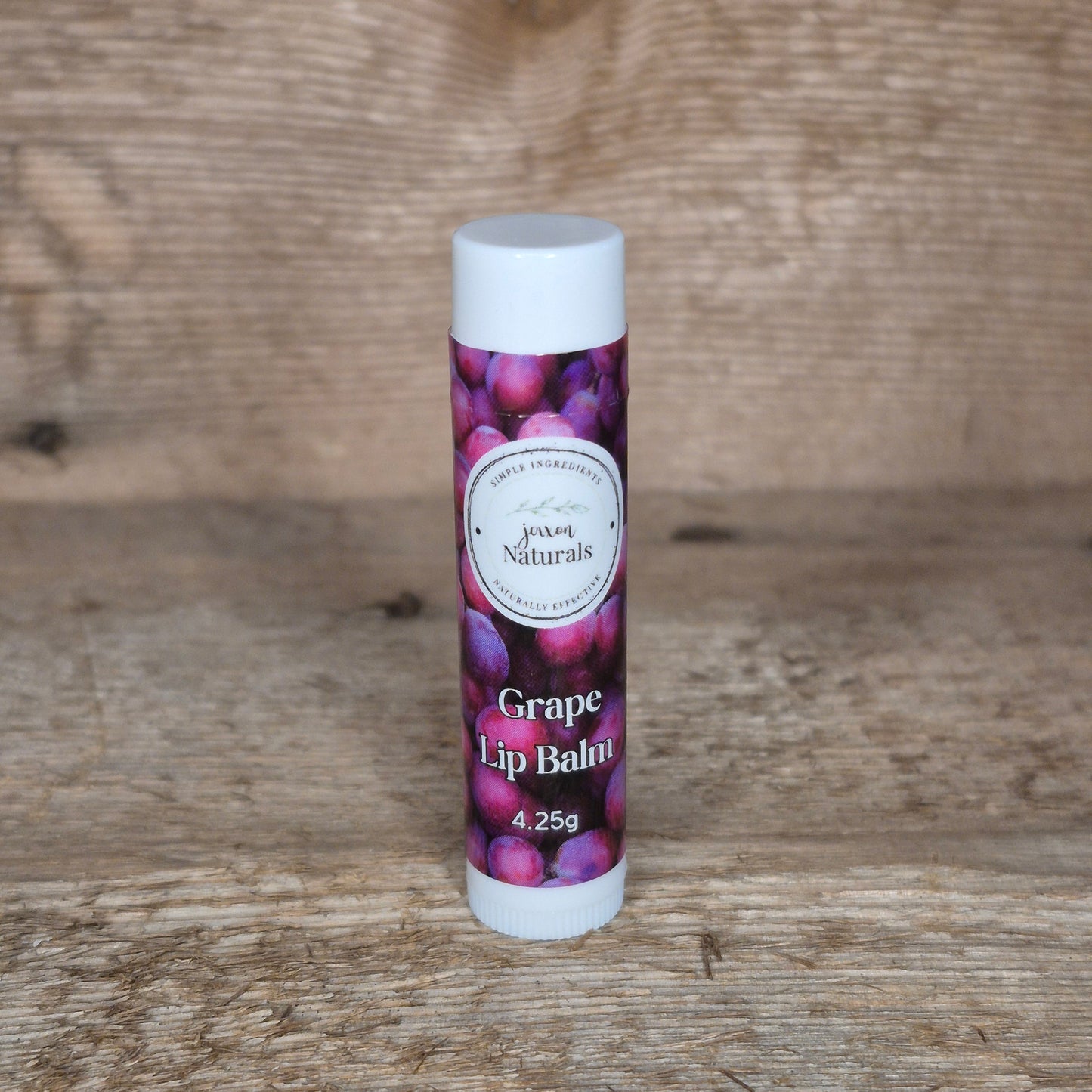 Jaxon Naturals limited edition grape lip balm displayed on rustic barn board.