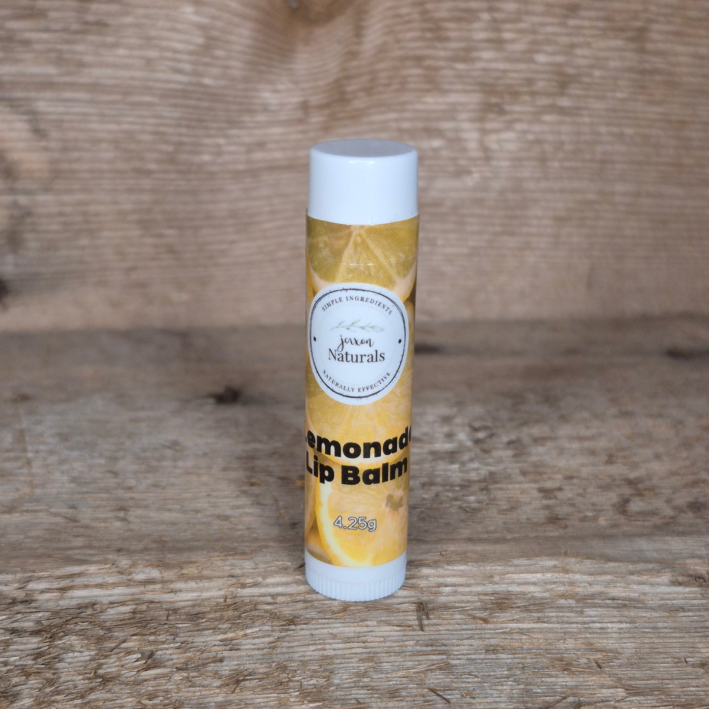 Jaxon Naturals limited edition lemonade lip balm displayed on rustic barn board.