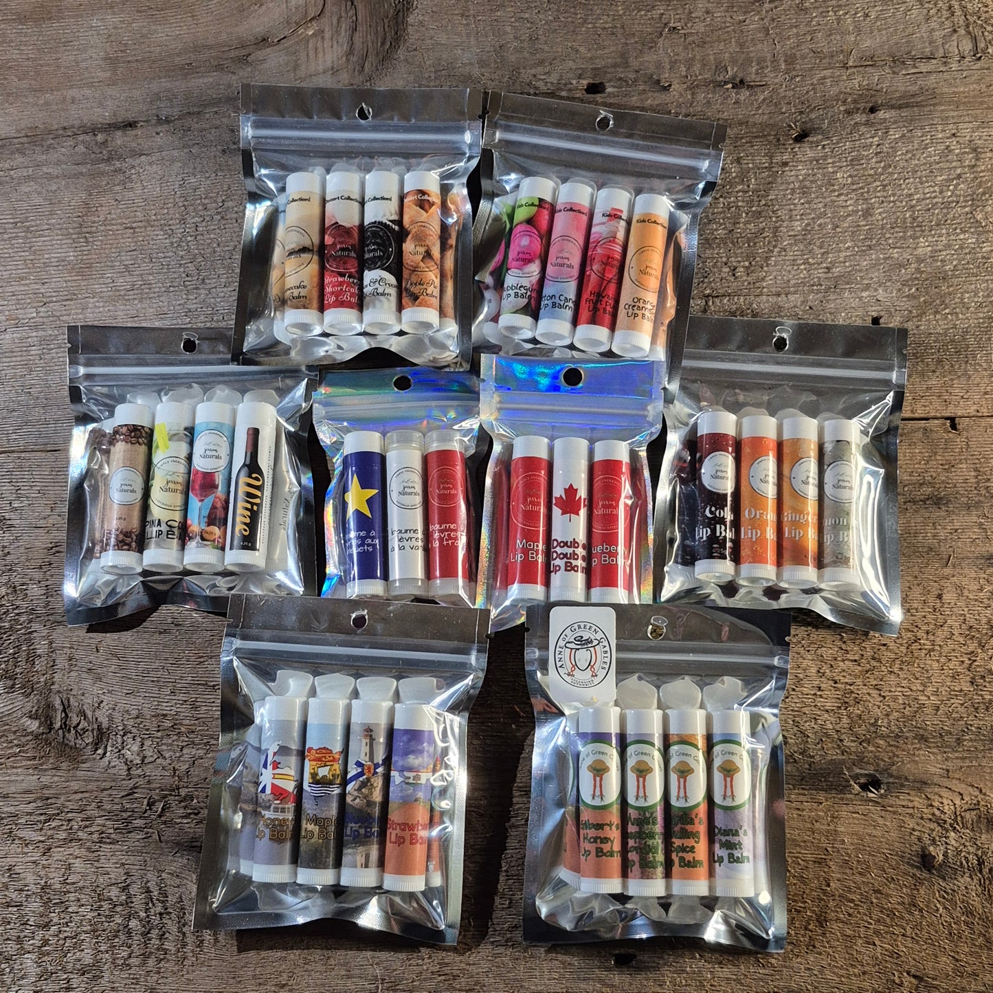 Eight Jaxon Naturals lip balm collections displayed together on rustic barn board, featuring handcrafted lip balms for every age and season.