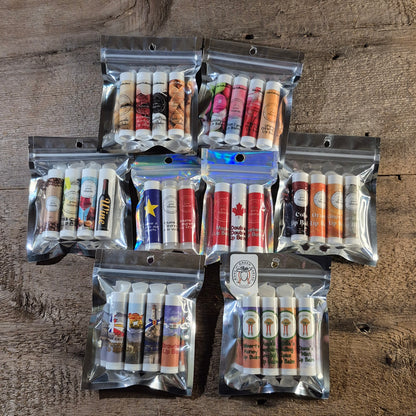 Eight Jaxon Naturals lip balm collections displayed together on rustic barn board, featuring handcrafted lip balms for every age and season.
