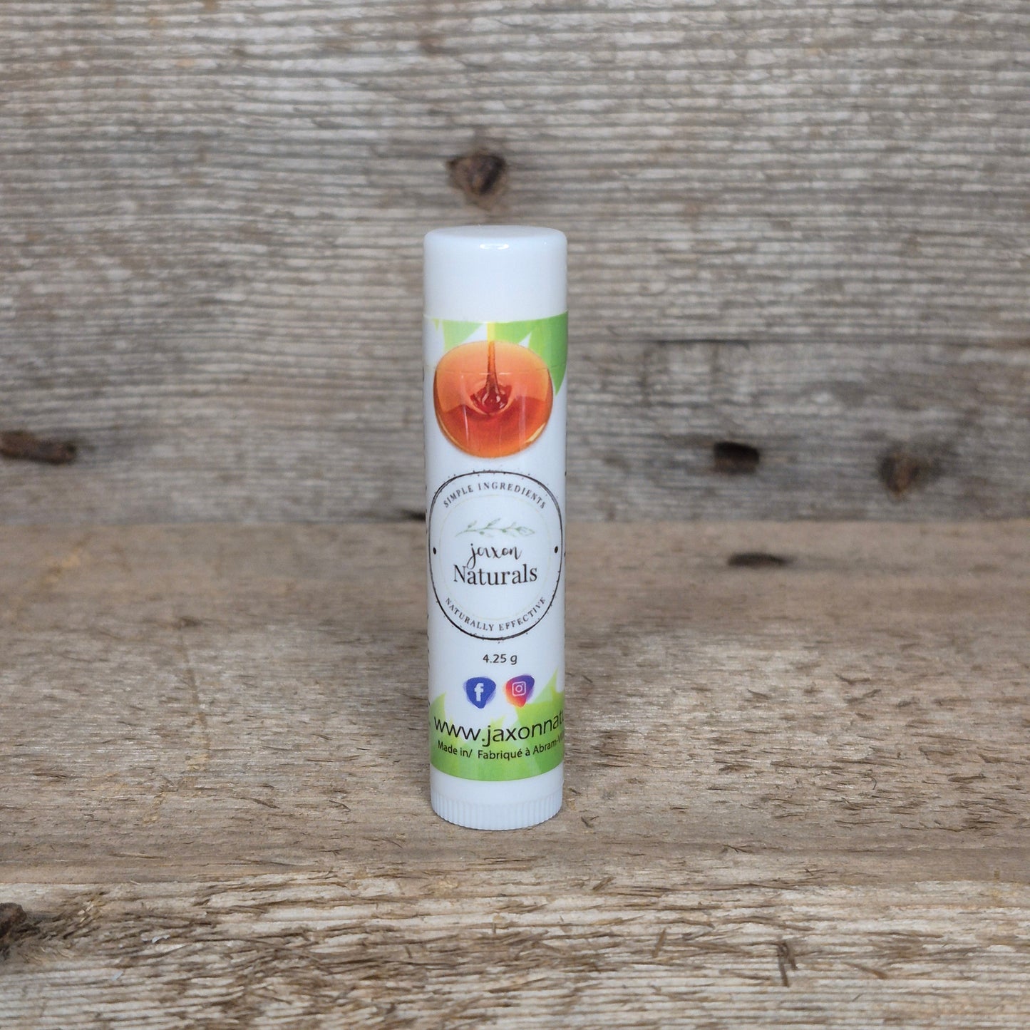 Jaxon Naturals Maple Lip Balm in a recyclable tube, handcrafted with natural ingredients and displayed on rustic barn wood.