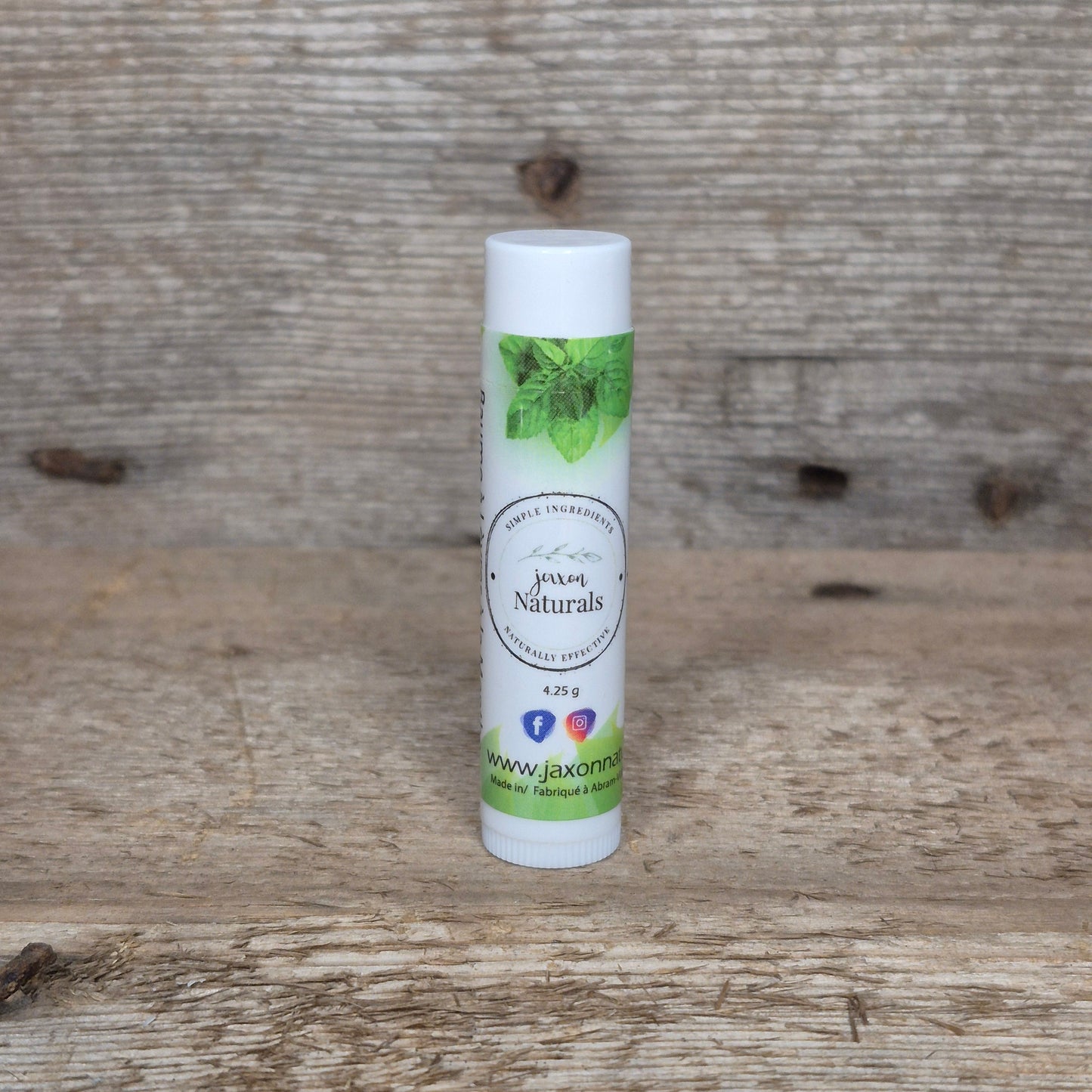 Jaxon Naturals Mint Lip Balm in a recyclable tube, handcrafted with natural ingredients and displayed on rustic barn wood.