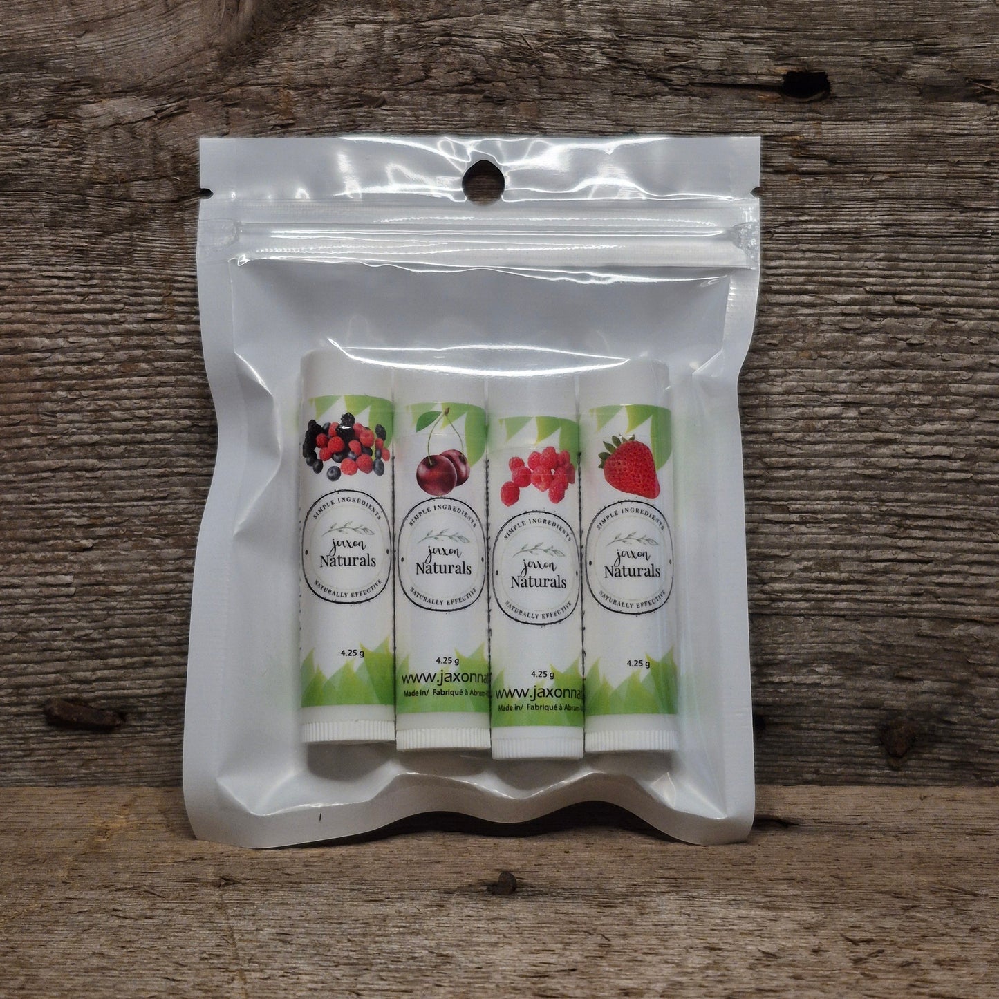 Jaxon Naturals Summer Lip Balm Collection featuring four handcrafted seasonal lip balms displayed on rustic barn board.